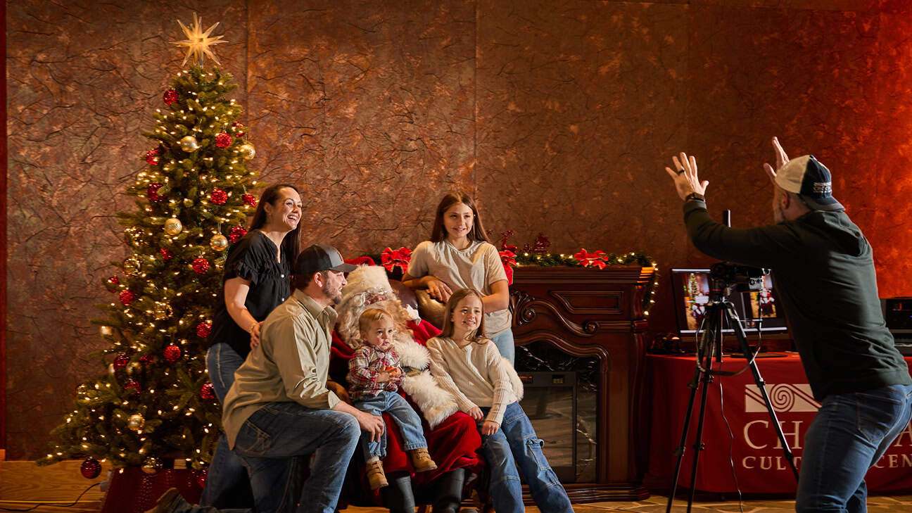 A family getting their picture taken in front of a Christmas Tree.