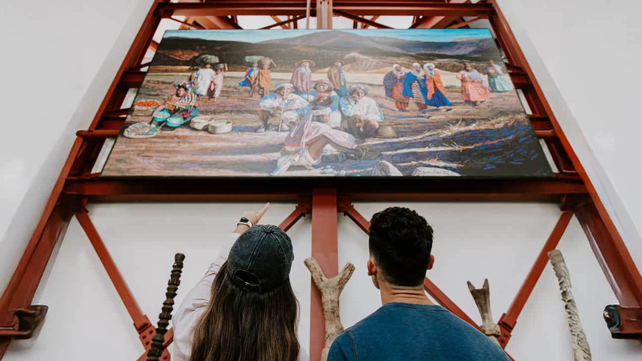 Two people looking at a painting in the Red River Museum.