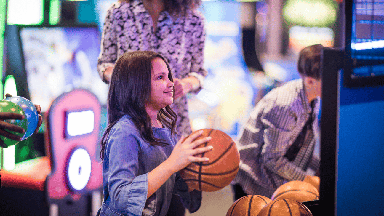 A little girl playing basketball at the District Arcade.
