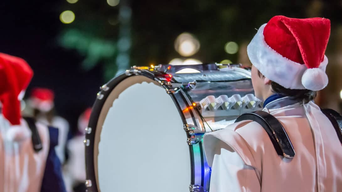 A student in the band marching with a drum.