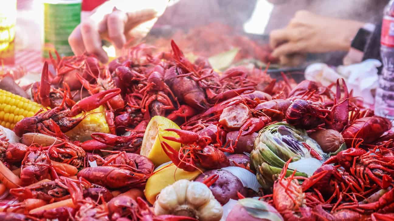 A heaping pile of crawfish with potatoes, brussels sprouts, and corn.