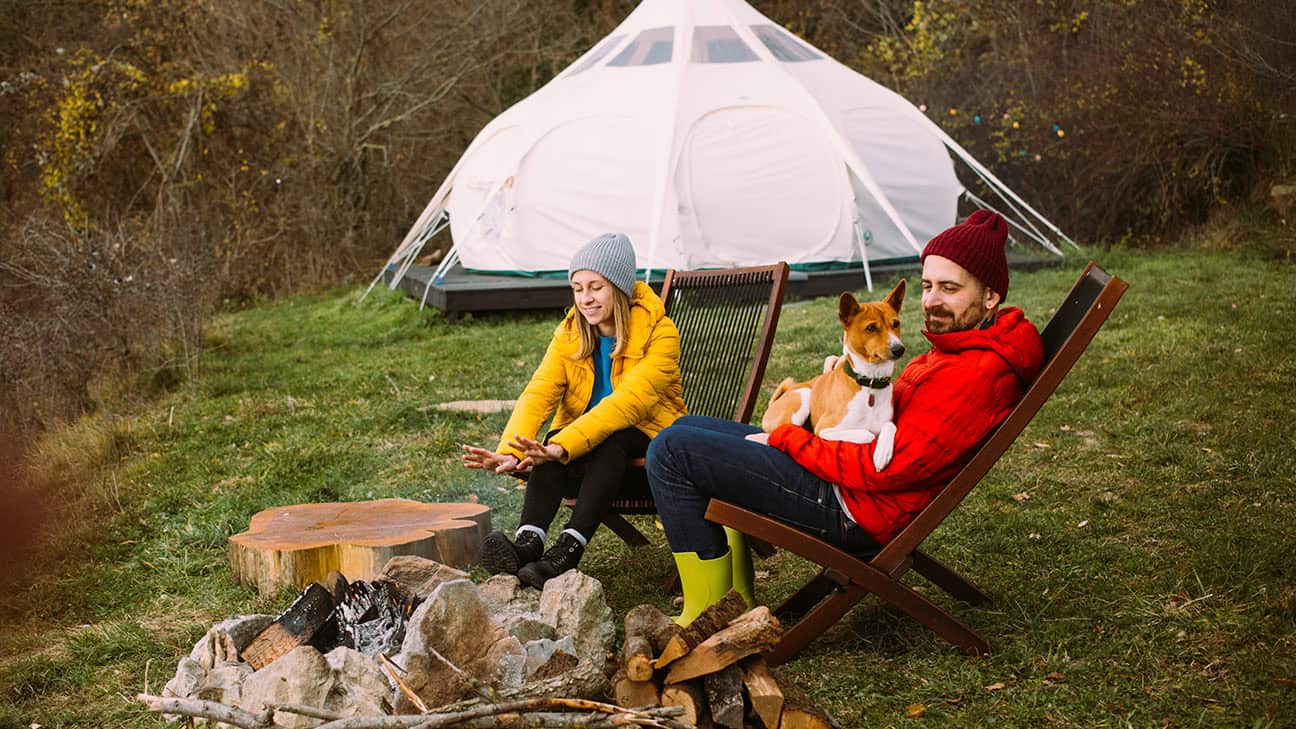 A couple sitting outside of a yurt.