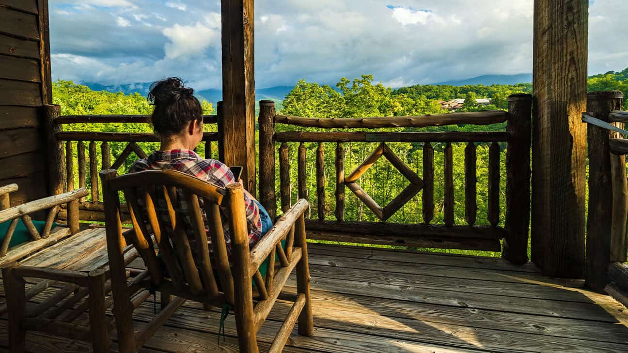 A woman sitting and looking out from a balcony.